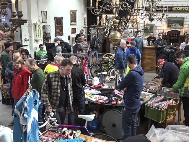 Der Teilchenbeschleuniger ist der grösste Secondhand und Veloteile Flohmarkt der Schweiz. Viele Menschen stehen in einem Raum, auf Tischen liegen Kleider und Fahrradteile zum Verkauf.