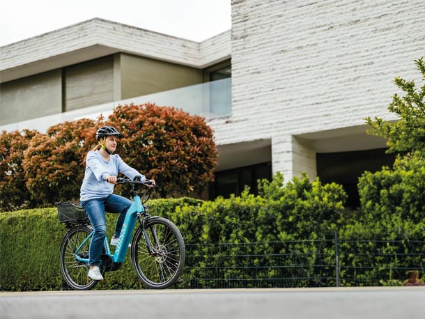 E-Bikes von Tour de Suisse sind künftig Teil des Angebots von Allride. Allride und Rent a Bike gehen Partnerschaft ein. Eine junge Frau fährt auf einem blauen E-Bike.
