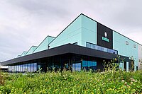 Binachi Fahrradfabrik Italien. Fabrikhalle mit grünen Wänden, davor eine Blumenwiese.
