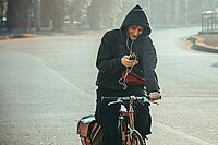 Ein Radfahrer hat ein Smartphone in der Hand während des Fahrens.