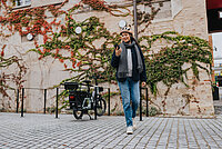 Abgeschlossenes E-Bike und Besitzerin mit Smartphone.