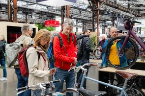 Besucher sehen sich an der Cyclingworld in Düsseldorf Fahrräder an einem Messestand an.