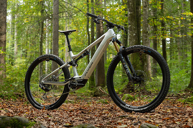 Flyer «Uproc SL:X». E-Mountainbike steht im Wald auf Laubboden.