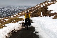 Ein Mann fährt mit dem Fahrrad auf einer schneebedeckten Strasse.