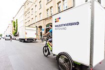 Ein grosses Lastenvelo fährt durch eine Strasse.