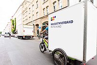 Ein grosses Lastenvelo fährt durch eine Strasse.