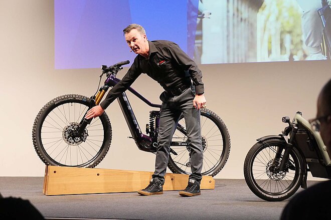 Bosch präsentiert an der Eurobike die neue Generation des Smart System. Ein Mann steht vor einem E-Mountainbike. 