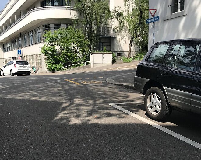 Eine Kreuzung mit Veloweg und Autos.