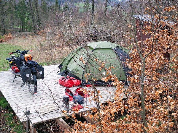 Gunnar Fehlau Workation. Ein Zelt steht auf einer Holzplattform im Wald.