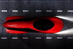 Ein rotes vollverschaltes Velomobil auf einem Fahrradweg.