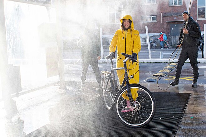 Was ist schon ein kleines bisschen Wasser? Der Overall hält dicht, selbst bei widrigsten Verhältnissen.
Eine Frau im gelben Overall wird mit Wasser bespritzt