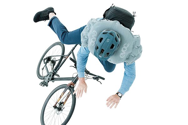 Eine Person fällt von ihrem Fahrrad und wird von einem Airbag vor dem Aufprall geschützt.