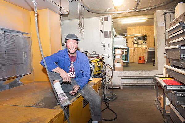 Ein Mann Sitzt in einer Werkstatt.