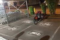 Frisch markierte Parkplätze für Cargobikes neben Einkaufswagen Station in der Nacht