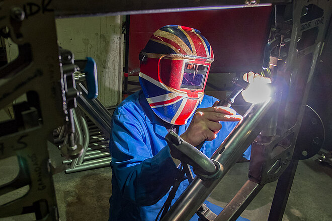 Orange Bikes ist insolvent. Eine Person mit Schweissmaske schweisst einen Fahrradrahmen.