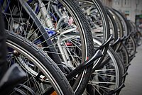 Viele Fahrradräder angekettet vor Betonmauer