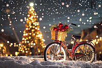 Rotes Velo mit Geschenkkorb am Lenker im Schnee vor Christbaum und Nachthimmel