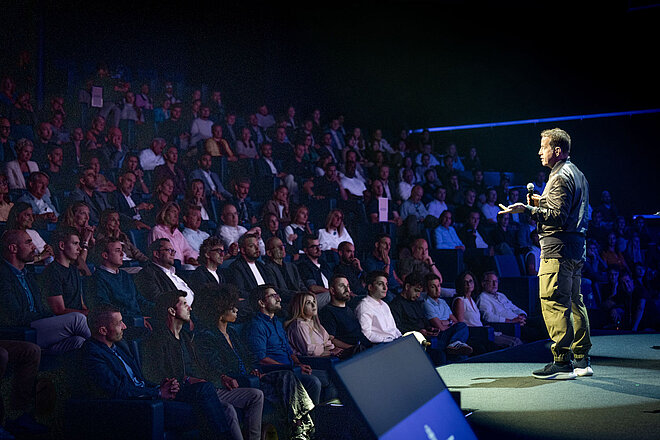 Ein Mann mit Mikrophon steht auf einer Bühne..