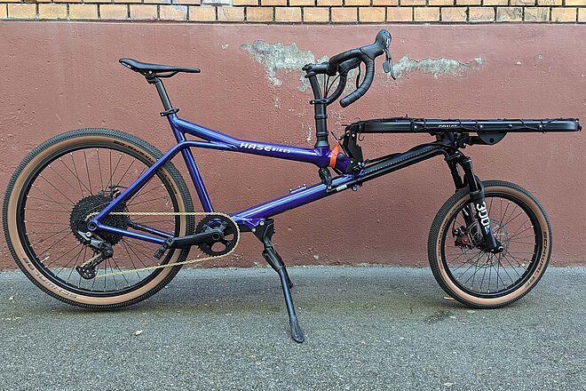 Test Hase Bikes Gravit Dust. Lastenrad mit violettem Rahmen und Ladefläche über dem Vorderrad.
