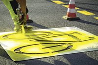 Ein Arbeiter sprüht ein gelbes Velossymbol auf die Strasse