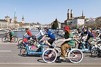 Ein bunter Tross von Menschen auf Velos, die in der Stadt Zürich über eine Brücke fahren.