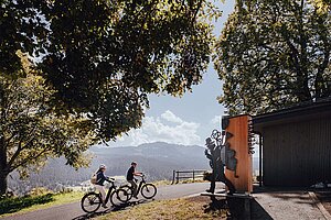 	Eine Frau und ein Mann radeln einen Hügel hinauf auf E-Bikes.