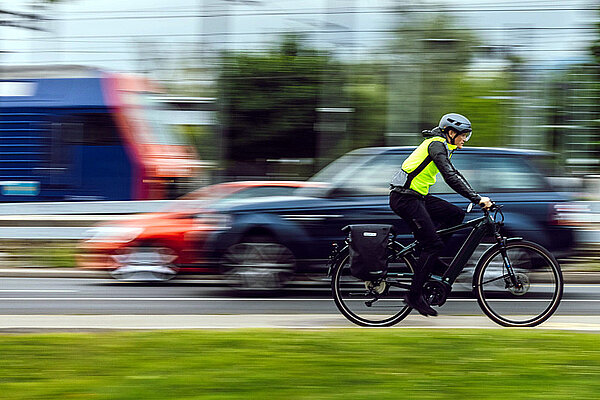 Tachopflicht für schnelle E-Bikes in der Schweiz. Eine Person mit gelber Leuchtweste fährt auf einem E-Bike. 