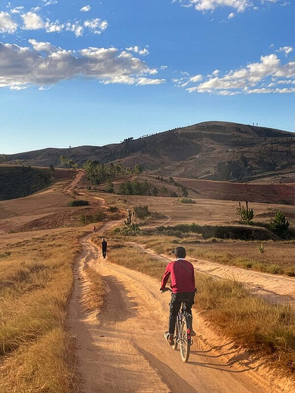 Eine Person fährt mit dem Fahrrad auf einer staubigen Piste auf Madagaskar.