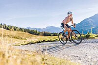 Die besten Gravelbikes des Jahres 2023. Eine Frau fährt mit dem Gravelbike auf einem Schotterweg.