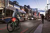 Ein Radfahrer fährt mit rotem Rücklicht in der Dämmerung