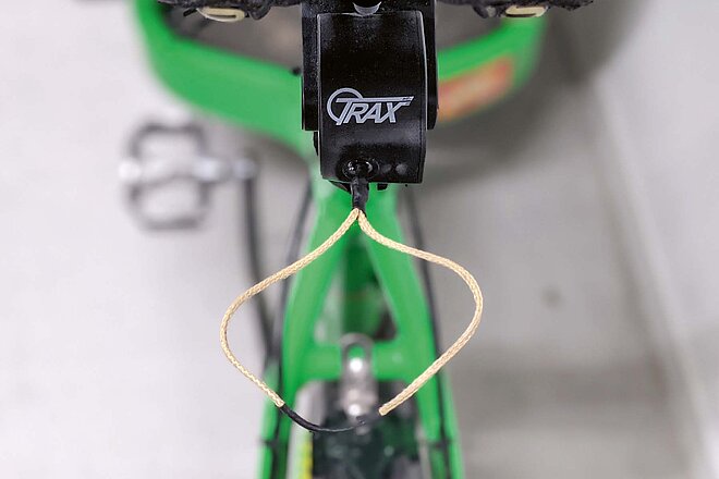 Um ein Kind in Schlepptau zu nehmen, wird die kleine Lasche einfach am Vorbau des Kindervelos eingehängt. (Foto: Fabian Baumann) Lasche eines Abschleppseils für Kindervelos