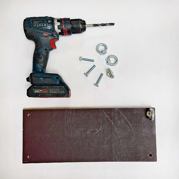 Ein Bohrer und Schrauben liegen auf einem Tisch.