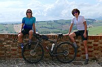 Die zwei Velofahrerinnen Cicliste Per Caso Silvia Gottardi und Linda Ronzoni mit Velo vor einer Mauer