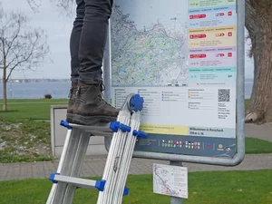 Eine Leiter lehnt an einem Schild. 