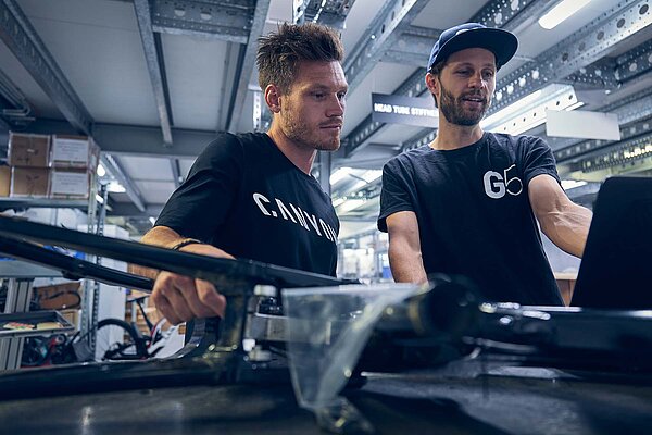 Canyon Innovation Lab. Zwei Männer arbeiten an einem Fahrrad.