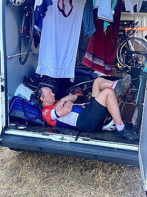 Mit dem Rennrad durch Korsika. Ein Mann macht im Kofferraum eines Autos ein Nickerchen.