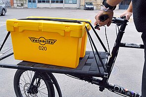 Eine gelbe Kiste steht auf der Ladefläche eines Lastenrads.