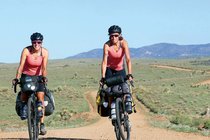 Zwei Frauen fahren mit Velos durch eine Wüste