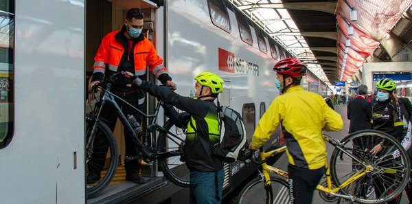 Ein SBB Mitarbeiter hilft beim Verladen von Fahrrädern in das Gepäckabteil eines Zugs