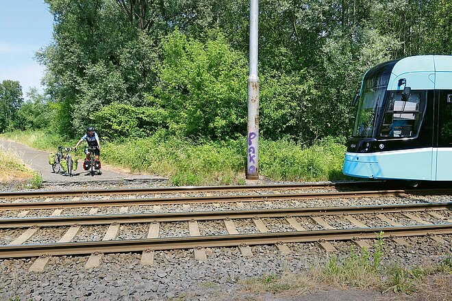 Die Ausfahrt aus Ostrava ist nicht leicht zu finden. Der Fotograf hat diese Hürde überwunden. Fahrradreise vier Länder Mitteleuropa. Ein Mann wartet mit dem Fahrrad vor einem Bahnübergang.