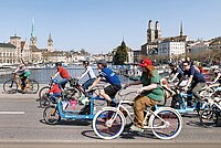 Ein bunter Tross von Menschen auf Velos, die in der Stadt Zürich über eine Brücke fahren.