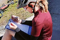 Eine Frau mit rotem Fahrradtricot sitzt auf dem Boden.