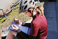 Eine Frau mit rotem Fahrradtricot sitzt auf dem Boden.