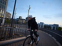 Mann mit weissem Uvex Velohelm fährt in der Dämmerung einer Brück entlang