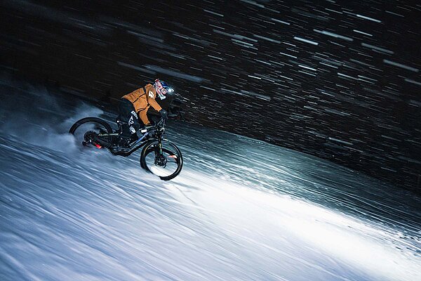Ein Biker fährt mit dem Mountainbike im Schnee.