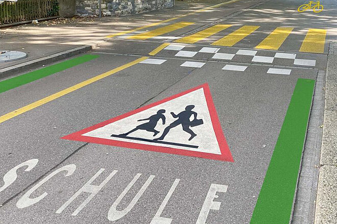 Velovorzugsroute mit grüner Markierung, achtung Schulkinder-Schild und Berliner Kissen