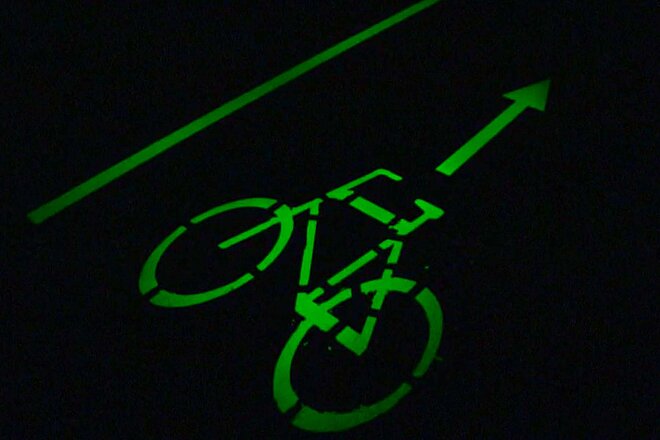 Ein Velosignet leuchtet in grüner Farbe in der Dunkelheit