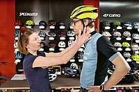 Aktuelle Fahrradhelme im Test. Eine Frau stellt die Riemen eines Velohelms ein. 