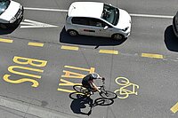 Strasse mit weissen Autos und separate Spur Velo, Bus und Taxi