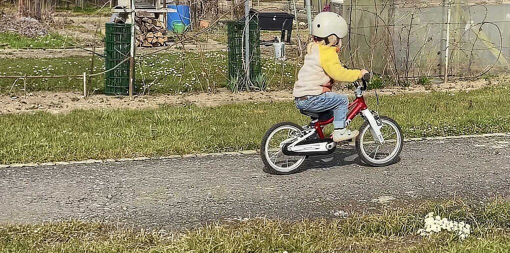 Ein Kind fährt auf einem Kinderad. 